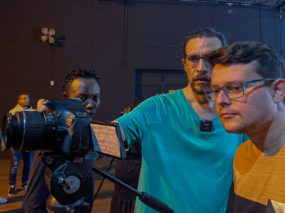 Alunos da Oficina de Light-Painting e Animação realizado no Tendal da Lapa conversam e trocam experiências enquanto manuseiam câmeras em um ambiente com pouca iluminação.